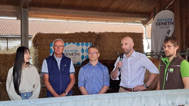 Vier Männer und eine Frau stehen vor Strohballen