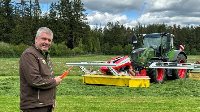 Ein Mensch vor einem Traktor mit Sensosave-Mähwerksaufrüstung