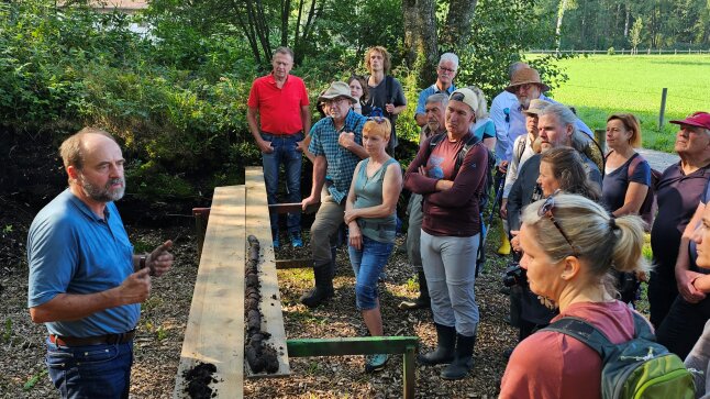 20 Personen stehen vor einer Person im Moor