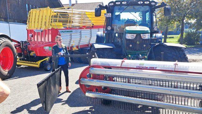 Traktor mit Striegel und Anhänger im Hintergrund