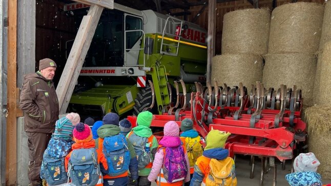 Leiter erklärt vielen Kindern große Landwirtschaftsmaschinen