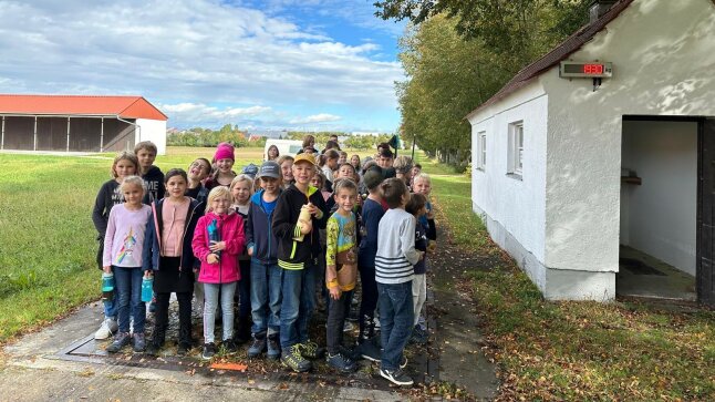 viele Kinder stehen auf einer Fuhrpark-Waage neben einer offenen Garage