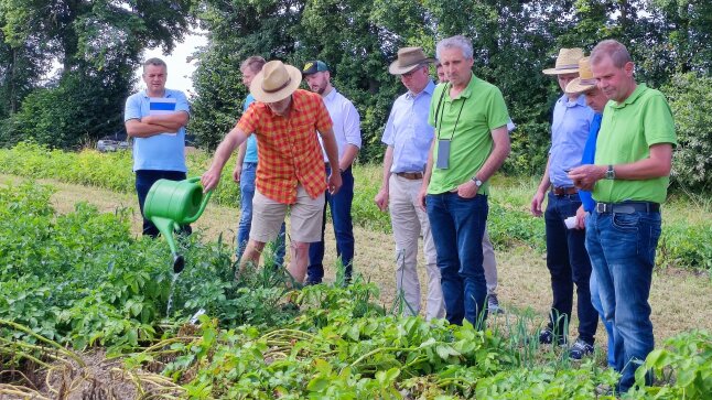 Gruppe Personen schaut auf Mann mit Gießkanne