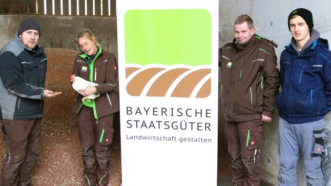 Vier Personen mit Henne vor Körnerhirselager
