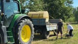 2 personen befüllen ihre Gieskannen an einem Traktorfass