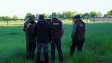 5 Männer und eine Frau stehen auf einer grünen Wiese und besprechen sich