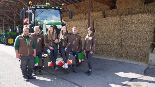 6 Personen stehen vor einem Traktor